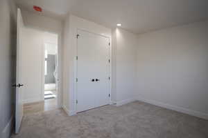 Unfurnished bedroom with carpet floors, a closet, baseboards, and recessed lighting