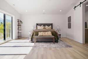 Bedroom featuring a barn door, light wood-style flooring, access to outside, recessed lighting, and baseboards