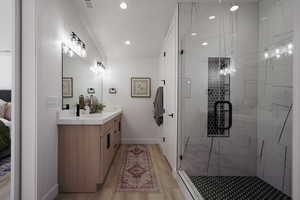 Ensuite bathroom featuring vanity, a stall shower, baseboards, wood finished floors, and recessed lighting