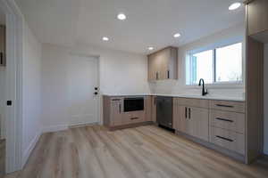 Kitchen with a sink, light brown cabinets, dishwasher, light wood-style flooring, and recessed lighting