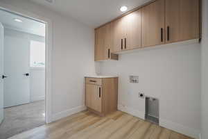 Washroom featuring electric dryer hookup, hookup for a washing machine, cabinet space, light wood-style flooring, and recessed lighting
