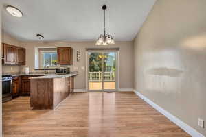 Kitchen with appliances with stainless steel finishes, light wood finished floors, a peninsula, hanging light fixtures, and a textured ceiling