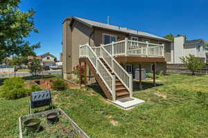 Back of house with a deck, a vegetable garden, stairway, and cooling unit