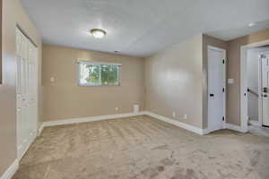 Unfurnished bedroom featuring carpet floors, a textured ceiling, and baseboards