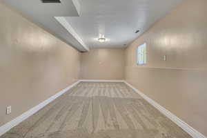 Basement with a textured ceiling, carpet floors, and baseboards