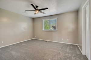 Unfurnished room with ceiling fan, a textured ceiling, carpet flooring, and baseboards
