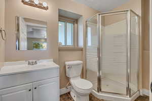 Bathroom with baseboards, a stall shower, vanity, and toilet