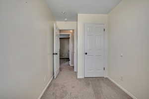 Hallway featuring light carpet and baseboards
