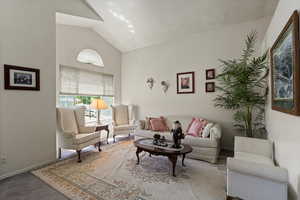 Living area featuring high vaulted ceiling, carpet floors, and baseboards