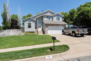 View of front of property featuring an attached garage, concrete driveway, and brick siding