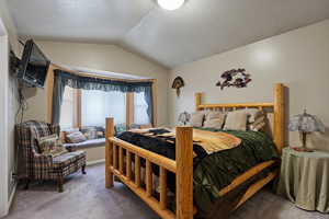 Bedroom with vaulted ceiling, carpet flooring, and a textured ceiling
