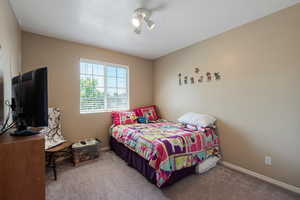 Carpeted bedroom featuring baseboards and ceiling fan