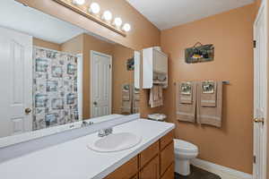 Full bathroom with toilet, vanity, baseboards, a shower with curtain, and tile patterned floors