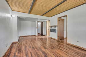 Spare room with wood finished floors, wooden ceiling with exposed beams, and baseboards