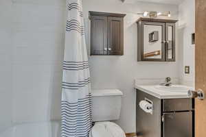 Bathroom featuring toilet, vanity, and shower / bath combo with shower curtain
