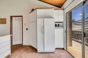 Kitchen featuring white fridge, stainless steel microwave, vaulted ceiling, white cabinets, and wooden ceiling