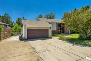 View of front facade with driveway, a garage, and roof with shingles