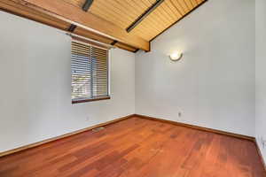 Empty room with baseboards, wood finished floors, and wood ceiling