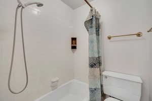 Full bath with shower / bath combo with shower curtain and toilet