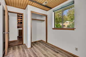 Unfurnished bedroom featuring wood ceiling, a closet, wood finished floors, and baseboards
