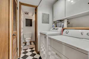 Laundry area featuring independent washer and dryer, electric panel, and light flooring