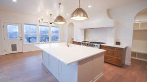 Kitchen with range, a sink, arched walkways, light wood-style floors, and a chandelier