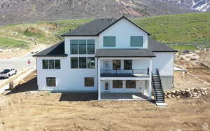 Back of house with a patio area, a mountain view, stairs, roof with shingles, and stucco siding