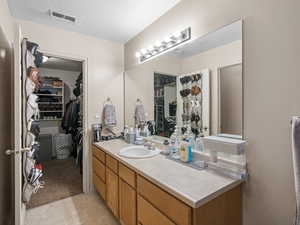 Bathroom featuring vanity, a textured ceiling, a spacious closet, and tile patterned flooring