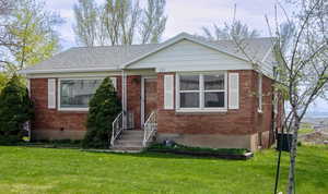 Bungalow featuring a front yard, brick siding, and central AC