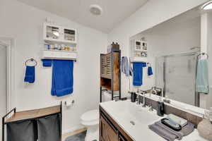 Bathroom with vanity, a shower stall, lofted ceiling, and tile patterned flooring