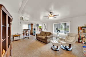 Living area with light carpet, healthy amount of natural light, ceiling fan, and vaulted ceiling