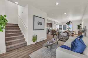 Living room with light wood-style flooring, recessed lighting, stairs, and baseboards