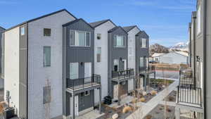 View of front of home featuring cooling unit, brick siding, board and batten siding, a balcony, and a mountain view