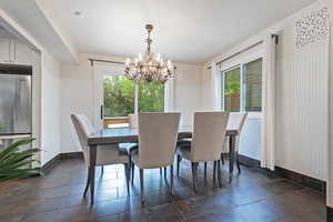 Dining space featuring healthy amount of natural light, a chandelier, and baseboards