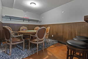 Dining room with wainscoting, finished concrete flooring, and wooden walls