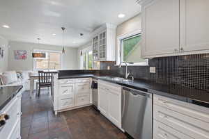Kitchen with stainless steel dishwasher, a sink, dark countertops, a peninsula, and recessed lighting