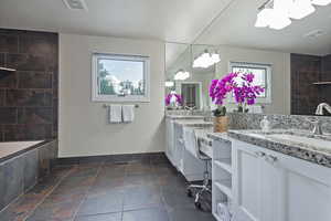 Full bathroom with plenty of natural light, double vanity, and baseboards