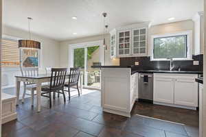 Kitchen featuring dark countertops, glass insert cabinets, decorative backsplash, a peninsula, and white cabinetry