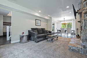 Living room featuring carpet flooring, a chandelier, recessed lighting, baseboards, and stairway