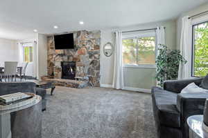 Living room with carpet, baseboards, a stone fireplace, and recessed lighting