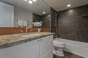 Full bath featuring vanity, shower / bath combination, toilet, recessed lighting, and tasteful backsplash