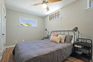 Bedroom with wood finished floors, baseboards, a textured ceiling, and ceiling fan