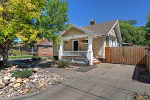 View of front of property with a porch, a chimney, roof with shingles, and a gate