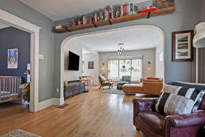 Living room featuring arched walkways, light wood-type flooring, and baseboards