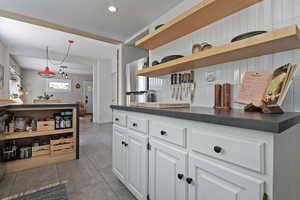 Kitchen featuring freestanding refrigerator, open shelves, dark countertops, white cabinets, and recessed lighting