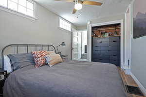 Bedroom with wood finished floors, a textured ceiling, ceiling fan, ensuite bath, and a closet