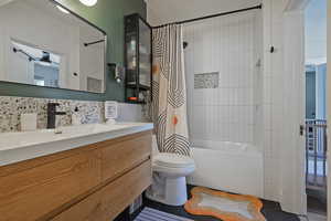 Bathroom with shower / bath combo, vanity, toilet, backsplash, and tile patterned flooring