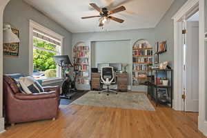 Office with a ceiling fan, wood-type flooring, and built in features