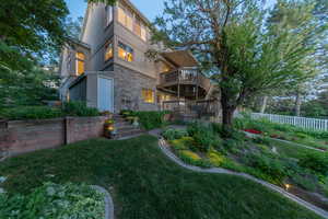 Back of property with stucco siding, stone siding, and a wooden deck.  Garden shed attached.