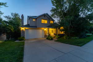 Traditional home featuring a garage, a chimney, driveway, and a front lawn